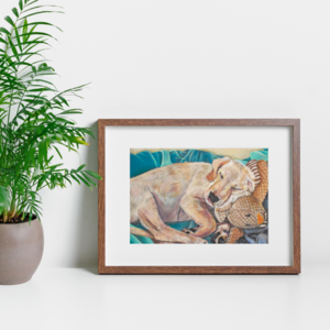 A mockup of the young puppy image in a mount and frame next to a lush green plant.